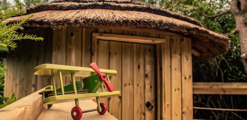 Toy plane sitting on a balustrade in front of a thatched and timber Treehouse.