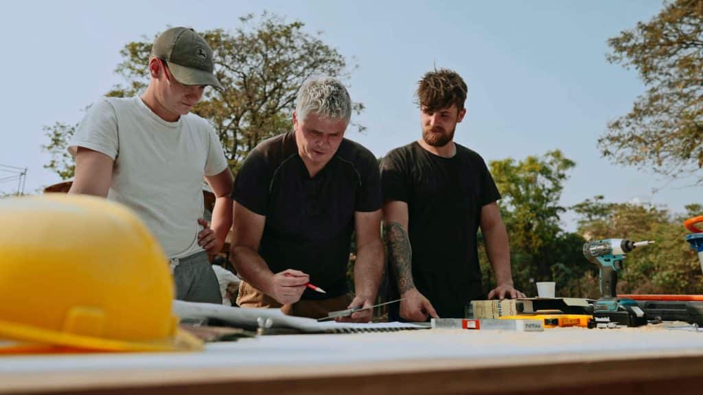 Family business - Paul Cameron with sons Elliott and Charlie working at a site table on a treehouse project.