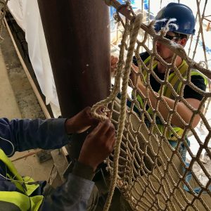 Two persons working either side of a Rope Balustrade installation on a building site in Qatar.