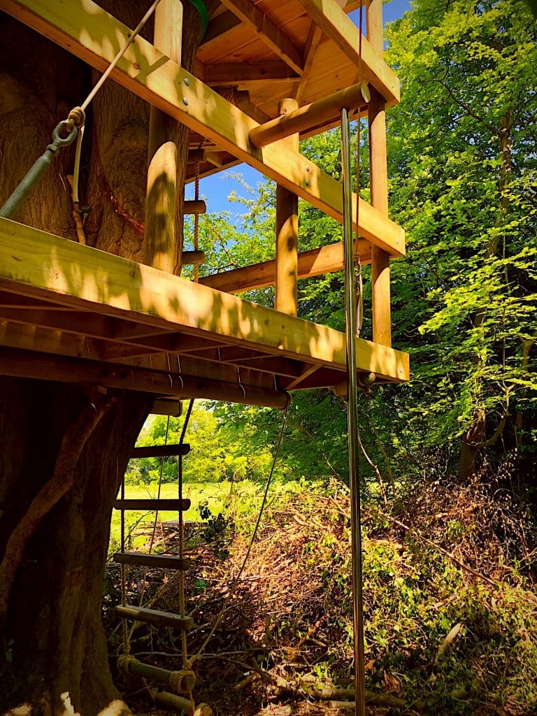 A fireman's pole descending from a woodland tree deck