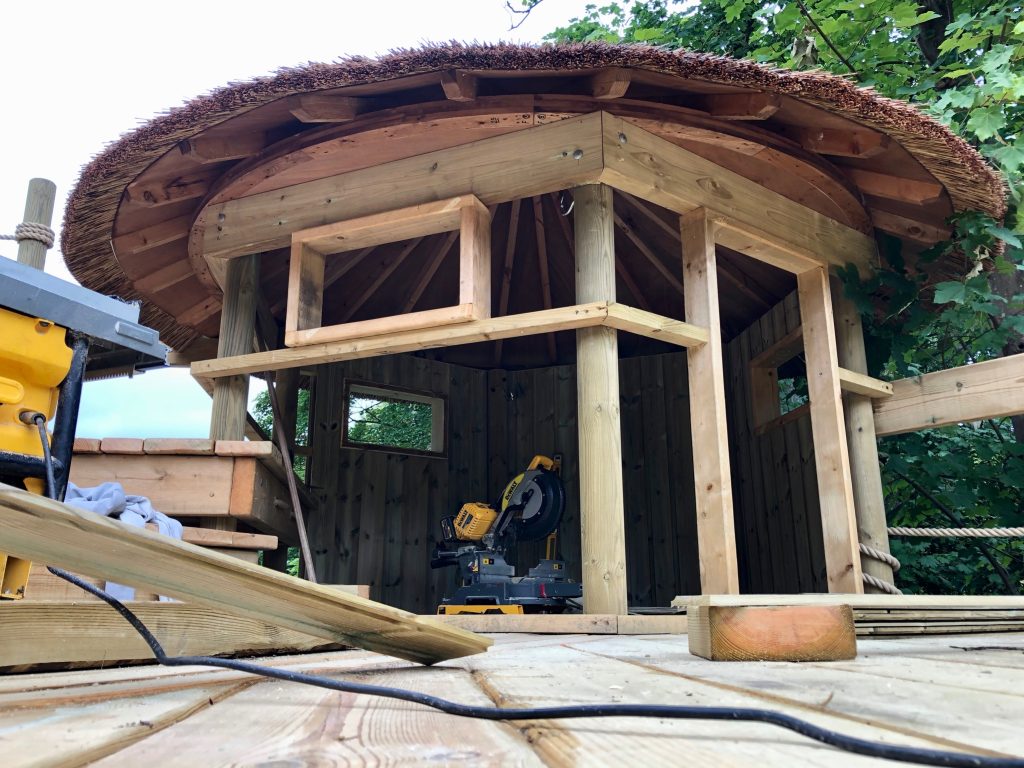 A treehouse halfway through construction and a selection of tools.