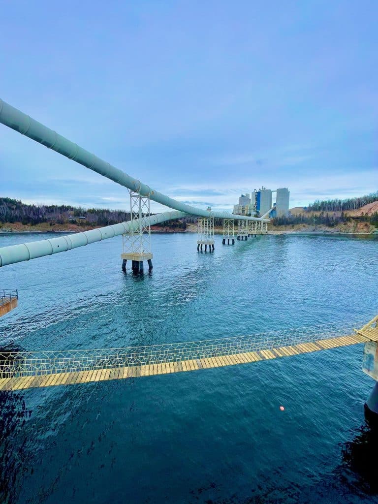 Timber Rope Bridge span above the sea between port dock dolphins at a commercial cement plant in Quebec, Canada